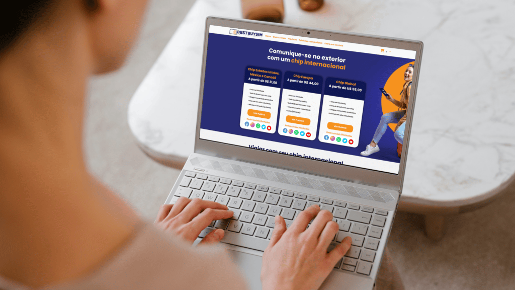 mulher digitando num computador branco que mostra, na tela, a página inicial do site best buy sim