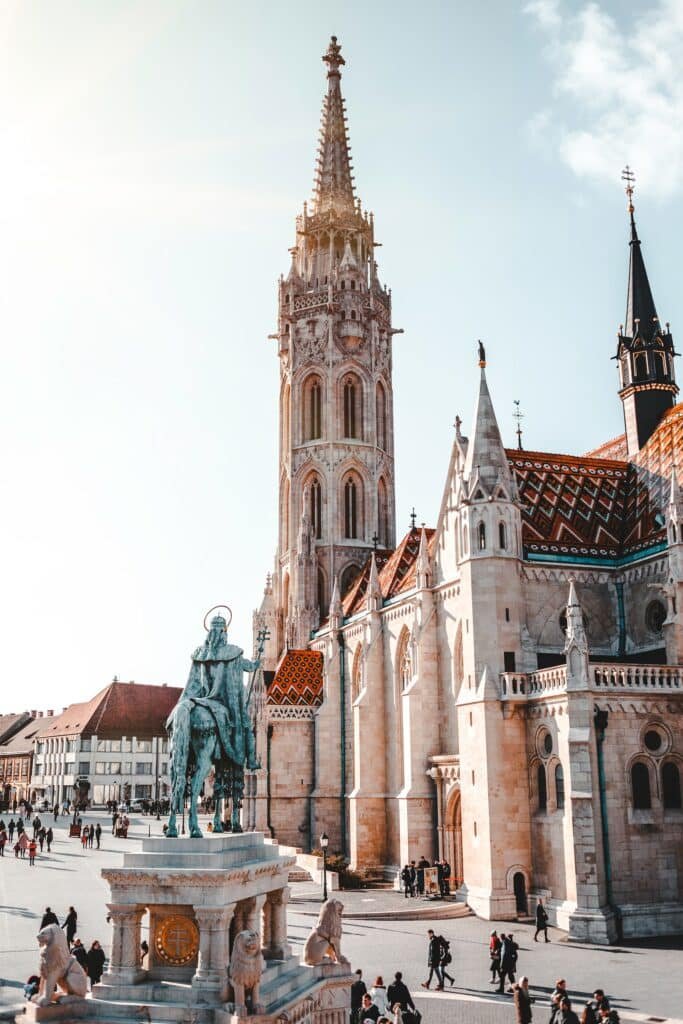 Estátua verde em frente a uma igreja bege durante o dia para ilustrar o post sobre chip de celular para Budapeste. - Foto: Florian van Duyn via Unsplash